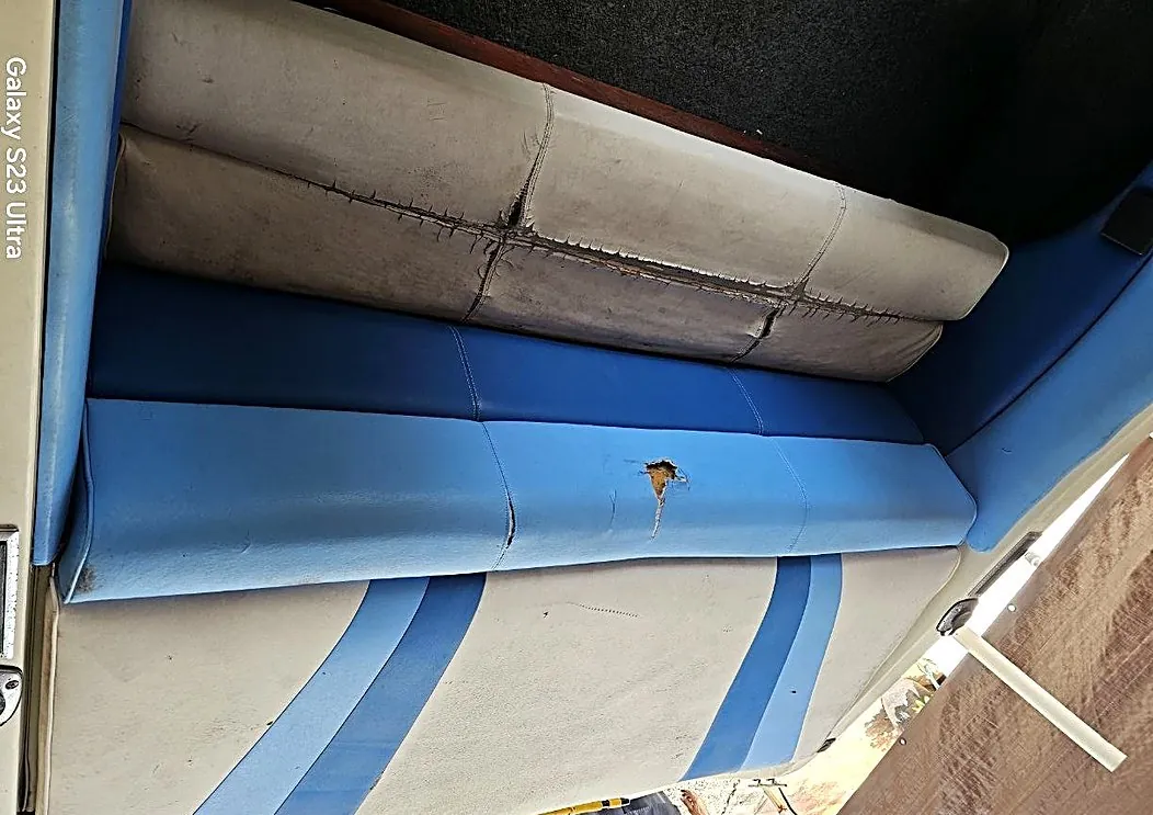 Sun-damaged boat bench with split seams and torn vinyl, before repair